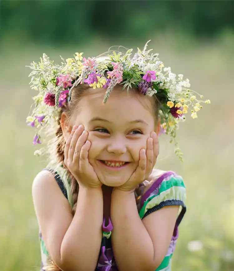 kleines Mädchen mit einem Kranz aus Wildblumen im Sommer